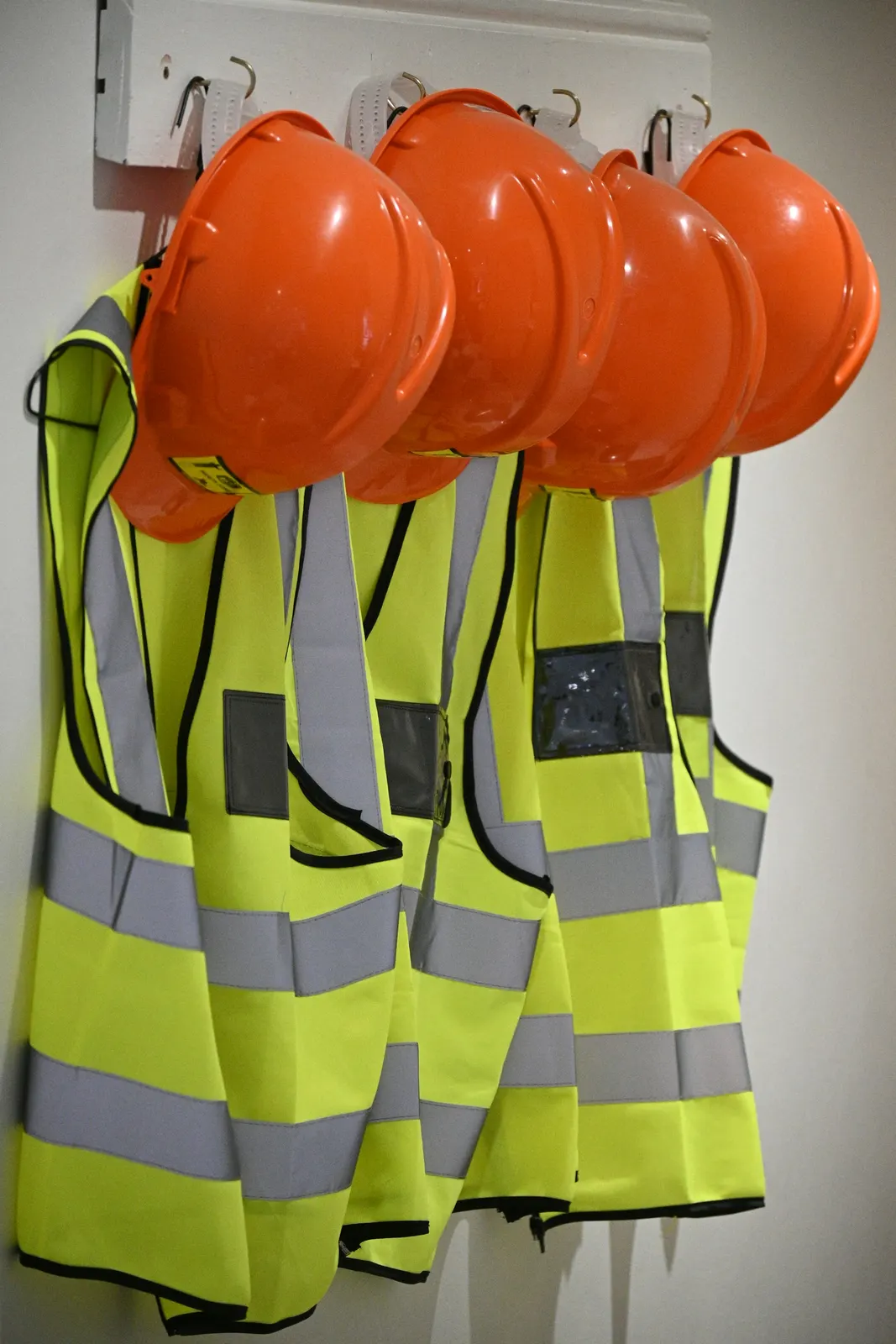 Oranje helmen en veiligheidshesjes aan de wand
